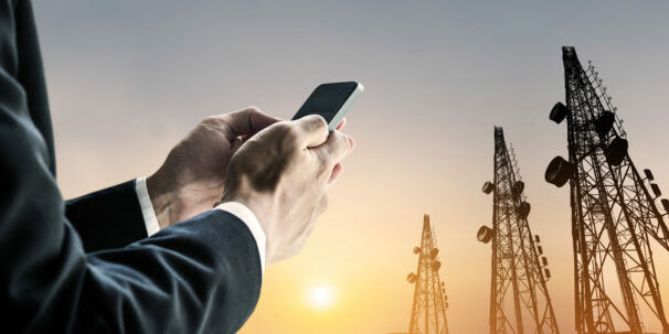 Businessman using mobile phone with multi exposure Telecommunication towers utility industry credit and collections