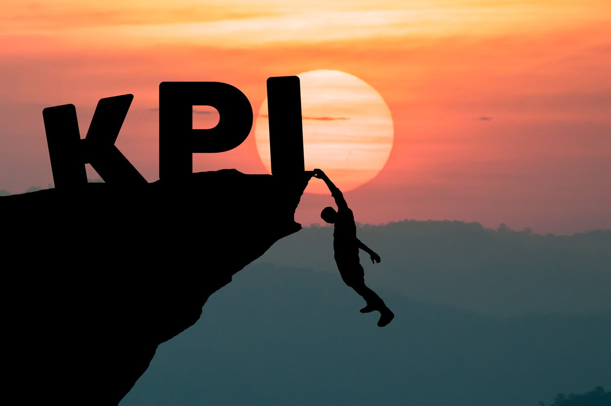 Young businessman climbing the mountain to achieve KPI with sunset background. (to reach key performance indicator) revenue cycle management