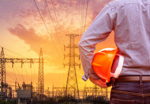 engineer holding yellow safety helmet with high voltage pylon on sunset energy industry accounts receivable