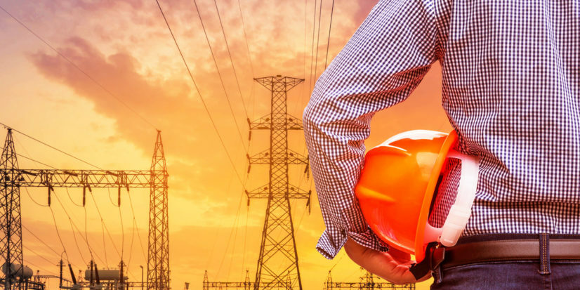 engineer holding yellow safety helmet with high voltage pylon on sunset energy industry accounts receivable