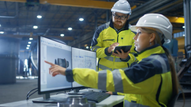 Inside the Heavy Industry Factory Female Industrial Engineer Works on Personal Computer She Designs 3D Turbine Model, Her Male Colleague Talks with Her and Uses Tablet Computer. energy industry accounts receivable