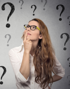 Woman in glasses surrounded by question marks