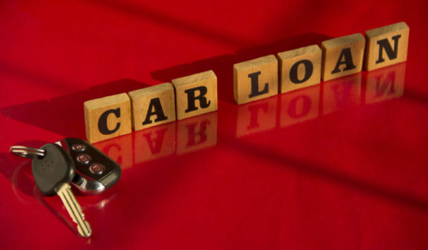 Wooden letters CAR LOAN with car key on a red background, financial concept car loan debt