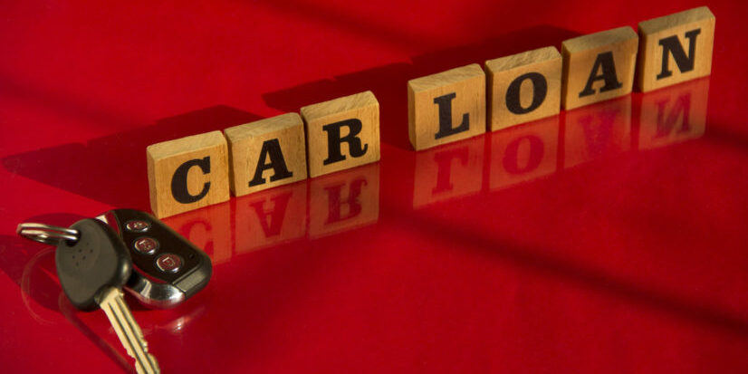 Wooden letters CAR LOAN with car key on a red background, financial concept car loan debt