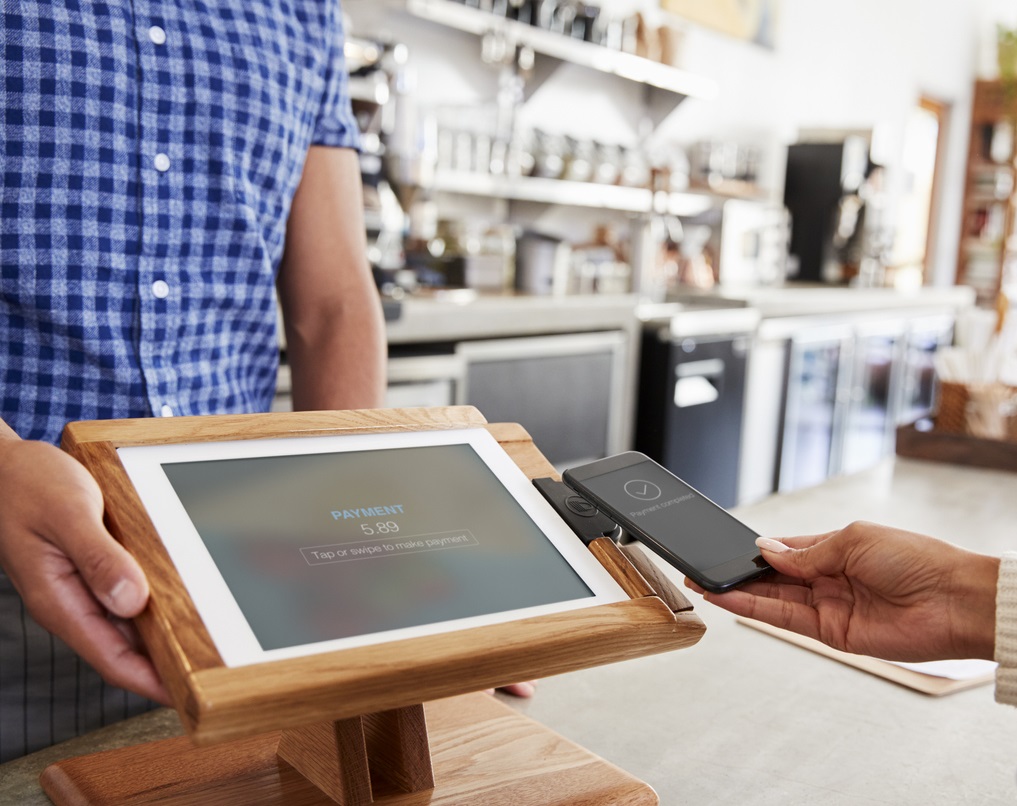 Woman making payment by smartphone at coffee shop, close up