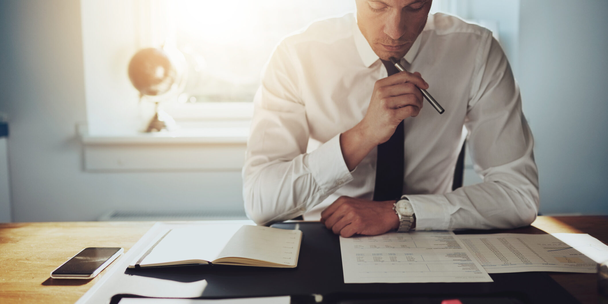 Serious business man working on documents Optio Solutions Man Studying